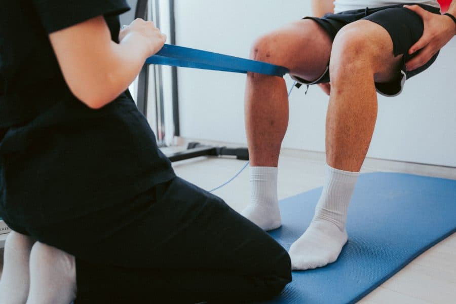 Trabajo de readaptación de rodilla con banda elástica sobre camilla